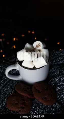 Becher mit Marshmallows und Chocolate Chip Cookies auf dunkle Weihnachten Hintergrund mit Lichtern - vertikale Foto Stockfoto