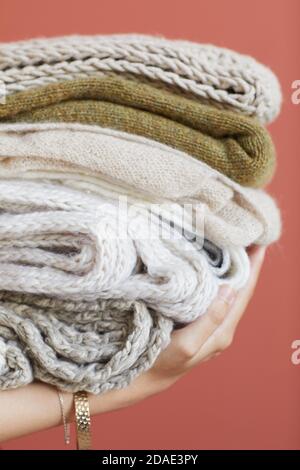 Nahaufnahme der weiblichen Hände, die einen Stapel Wollkleidung isoliert halten Auf rosa Hintergrund Stockfoto