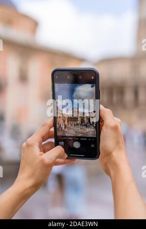 Hände einer Frau, die mit ihrem Handy ein Foto auf der Plaza de la Virgen, Valencia, Spanien macht. Stockfoto