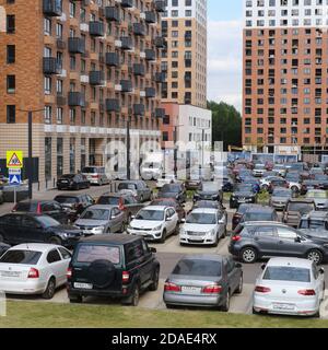 Autos werden auf dem Parkplatz in der Nähe des unfertigen neuen Gebäudes geparkt - Moskau, Russland, 20. August 2020 Stockfoto