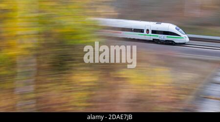 Sorsum, Deutschland. November 2020. Auf der Schnellstraße Hannover-Göttingen im Stadtteil Hildesheim fährt ein ICE der Deutschen Bahn an herbstlich verfärbten Bäumen vorbei (Aufnahme mit langer Verschlusszeit). Die Deutsche Bahn lässt ihre Kunden viel seltener warten als im vergangenen Herbst. Wie bereits im September waren 78.8 Prozent der Fernzüge im Oktober pünktlich, so ein Bahnsprecher der Deutschen Presseagentur. Damit stieg der Pünktlichkeitswert für ICE und Intercities gegenüber Oktober 2019 um 5.8 Prozentpunkte. Kredit: Julian Stratenschulte/dpa/Alamy Live Nachrichten Stockfoto