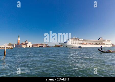 Venedig, Italien - 09.11.19: Gondel & riesiges Kreuzfahrtschiff im Giudecca Kanal. Viele Menschen behaupten, dass die Umweltauswirkungen von großen Kreuzfahrtschiffen Stockfoto