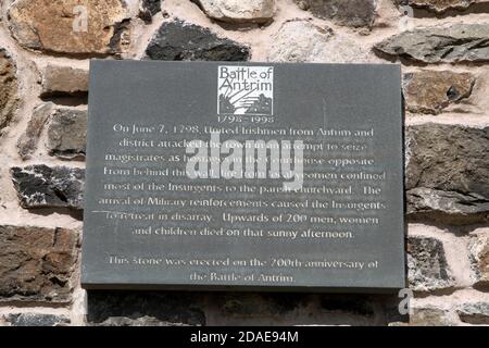 Antrim Nordirland. Gedenktafel zur Schlacht von Antrim am 7 1798. Juni. Am 200. Jahrestag der Schlacht von Antrim wurden Steinpfeiler und -Plakate errichtet. Am 7. Juni 1798 griffen vereinte Iren aus Antrim und dem Bezirk die Stadt an, um Richter als Geiseln im gegenüberliegenden Gerichtsgebäude zu ergreifen. Hinter dieser Mauer verbrannte das Feuer der lokalen Yeomen die meisten Aufständischen auf den Gemeindefriedhof. Das Eintreffen militärischer Verstärkung führte dazu, dass sich die Aufständischen im Chaos zurückzogen. Mehr als 200 Männer, Frauen und Kinder starben an diesem sonnigen Nachmittag. Stockfoto