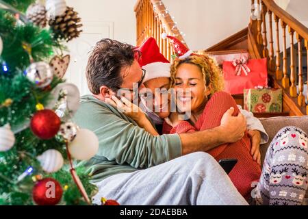 Glückliche Familie genießen zusammen weihnachten traditionellen Abend Tag mit Umarmung Und Lächeln - Konzept der echten Menschen zu Hause während Traditionelle Veranstaltung - Umarmung und Glück mit Ehemann Frau und Teenager Sohn verliebt Stockfoto