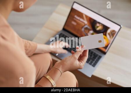 Nahaufnahme einer Frau, die vor dem Laptop sitzt und bestellt Essen online und mit Kreditkarte bezahlen Stockfoto