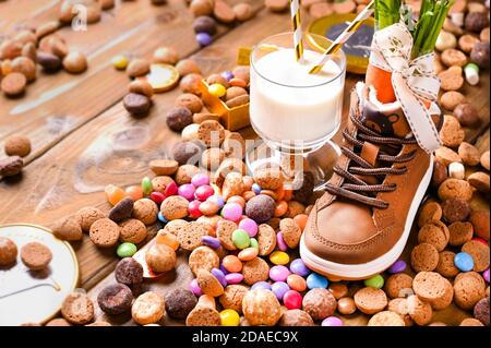 Holzhintergrund mit Kinderschuh mit Karotten für Santa's Pferd, Pepernoten und Süßigkeiten. Traditionelle niederländische Urlaubspostkarte Sinterklaas . Blick von oben. Speicherplatz kopieren. Hochwertige Fotos. Stockfoto