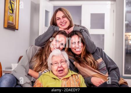Drei Enkelinnen mit ihrer Großmutter, die in die Kamera schaut Stockfoto
