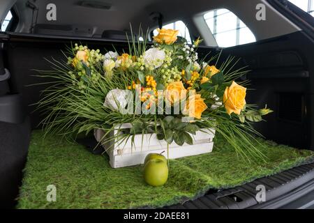 Äpfel und ein Korb mit Rosenblüten befinden sich im offenen Kofferraum eines Autos. Stockfoto