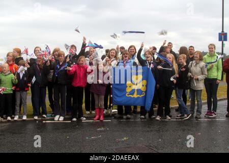 Maidens, Ayrshire, Schottland, Großbritannien. Die London 2012 Olympic Fackel reist durch South Ayrshire, angefeuert von lokalen Gemeinden und Schulkindern. Die lokale Mädchenführer-Gruppe winkt Stockfoto