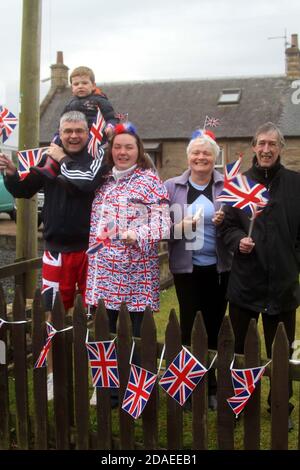 Maidens, Ayrshire, Schottland, Großbritannien. Die London 2012 Olympic Fackel reist durch South Ayrshire, angefeuert von lokalen Gemeinden und Schulkindern. Frau im Mantel von Union Jack Stockfoto