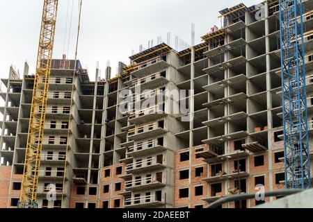 Fassade eines mehrstöckigen Wohngebäudes im Bau mit einem Kran davor. Stockfoto