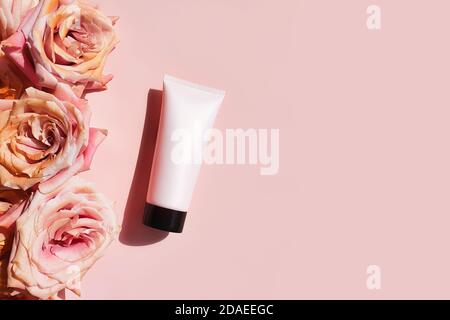 Draufsicht von Mock-up hellrosa Squeeze Flasche Plastikschlauch mit schwarzer Kappe und rosa goldenen Rosen auf einem pastellrosa Hintergrund. Flasche für Branding und l Stockfoto