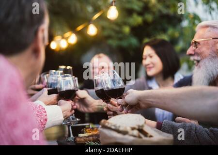 Happy Familie Essen und Verkostung Rotwein Gläser in Grill Abendessen Party - Menschen mit unterschiedlichen Alters und Ethnizität Spaß zusammen Stockfoto