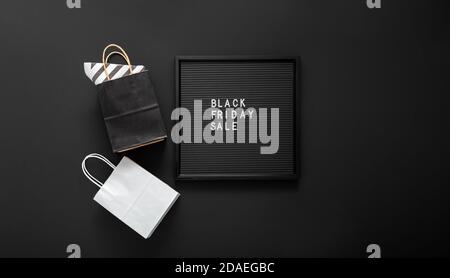 Schwarzer Freitagsverkaufstext auf schwarzem Briefbrett mit Einkaufstaschen auf schwarzem Hintergrund. Lieferung Mock up schwarz und weiß Handwerk Papiertüte Paket Stockfoto