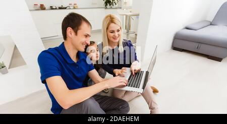 Glückliche Familie chatten online mit Laptop, während mit Baby zu Hause sitzen. Stockfoto