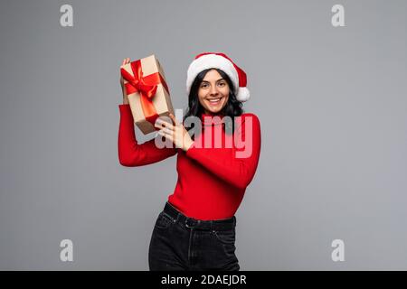 Glückliche europäische Santa Frau lächelt und hält Geschenk-Box für Weihnachten oder Neujahr. Isoliert auf grauem Hintergrund Stockfoto