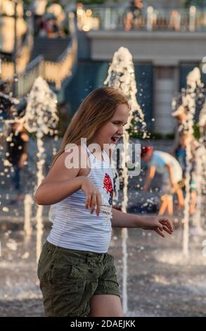 KIEW, UKRAINE - 05. Jun 2018: Fröhliches und glückliches Mädchen, das in einem Brunnen spielt und an einem heißen Tag die kühlen Wasserströme genießt. Heißer Sommer. Stockfoto