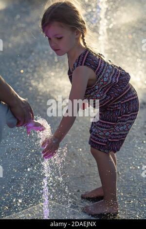 KIEW, UKRAINE - 05. Jun 2018: Fröhliches und glückliches Mädchen, das in einem Brunnen spielt und an einem heißen Tag die kühlen Wasserströme genießt. Heißer Sommer. Stockfoto