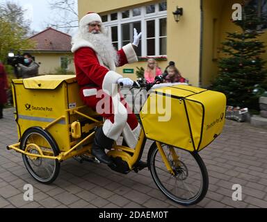 Himmelpfort, Deutschland. November 2020. Der Weihnachtsmann kommt mit einem Elektrofahrrad der Deutschen Post in Himmelpfort an. Bis Heiligabend wird er mit Unterstützung seiner 20 fleißigen Helfer die Kinderbriefe aus Deutschland und der ganzen Welt wieder beantworten. Aufgrund der anhaltenden Gefahr einer Coronainfektion wird es in diesem Jahr leider keine öffentlich zugängliche Weihnachtspost geben und der Weihnachtsmann und seine Engel können im Weihnachtsdorf nicht besucht werden. Quelle: dpa picture Alliance/Alamy Live News Stockfoto