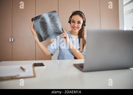 Fröhliche Ärztin mit Laptop für Online-Beratung Stockfoto