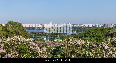 Kiewer Landschaften. Frühlingsansicht des Vydubychi-Klosters und des Flusses Dnipro mit rosa und weißen Fliederblüten im botanischen Garten in Kiew-Stadt, Ukraine Stockfoto