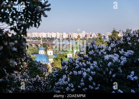 Kiewer Landschaften. Frühlingsansicht des Vydubychi-Klosters und des Flusses Dnipro mit rosa und weißen Fliederblüten im botanischen Garten in Kiew-Stadt, Ukraine Stockfoto