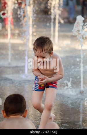 KIEW, UKRAINE - 05. Jun 2018: Fröhliche und glückliche Kinder, die in einem Brunnen spielen und an einem heißen Tag die kühlen Wasserströme genießen. Heißer Sommer. Stockfoto