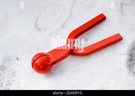 Leuchtendes rotes Kunststoffgerät, Spielzeugclip für die Herstellung von Schneebällen auf weißem Schneehintergrund. Glückliche Kindheit und Winter Spaß Spielkonzept. Stockfoto