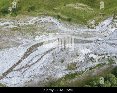 Steinerne Flussbett in der Hochsaison im Sommer von Grün umgeben alpenrasenland Stockfoto