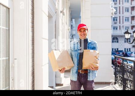 Lieferung, Post und Menschen Konzept - Mann liefert Kaffee und Essen in Einweg-Papiertüte nach Hause des Kunden Stockfoto