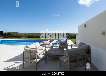 Terrasse Sitzbereich im Garten eines Luxusurlaubs villa mit Schwimmbad im Hintergrund Stockfoto