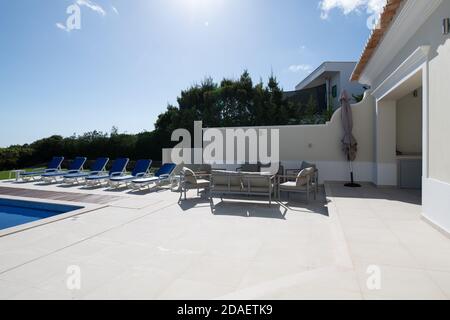 Terrasse Sitzbereich im Garten eines Luxusurlaubs villa mit Schwimmbad im Hintergrund Stockfoto