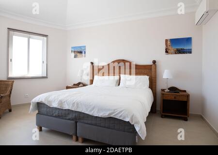 Hauptschlafzimmer mit Holzmöbeln und weißer Bettwäsche in einem Renovierte Ferienvilla Stockfoto