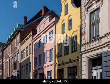 Lübeck in Norddeutschland. Diese hohen, pastellfarbenen Häuser im holländischen Stil sind in engen Gassen zu finden. Die Kirche der Heiligen Maria ist im Hintergrund. Stockfoto