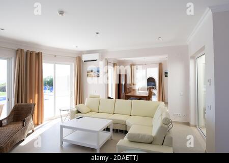 Modernes, sauberes Wohnzimmer des Luxus-Familienhauses mit großem L-förmigen Ledersofa und Fliesenböden Stockfoto