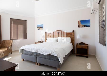 Hauptschlafzimmer mit Holzmöbeln und weißer Bettwäsche in einem Renovierte Ferienvilla Stockfoto