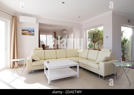 Modernes, sauberes Wohnzimmer des Luxus-Familienhauses mit großem L-förmigen Ledersofa und Fliesenböden Stockfoto