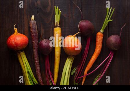 Blick von oben auf frische Bio-goldene und rote Rüben und Mehrfarbige Karotten auf einer Holzoberfläche Stockfoto