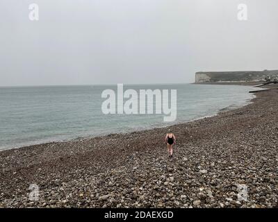 Nicht erkennbare Schwimmerin geht schwimmen im Meer im Regen, Opal-Küste, Normandie, Frankreich Stockfoto