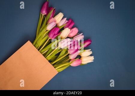 Bouquet von Tulpen in Bastelpapiertasche auf klassisch blauem Hintergrund. Urlaubskonzept. Gruß zum Frauen- oder Muttertag, Valentinstag Stockfoto