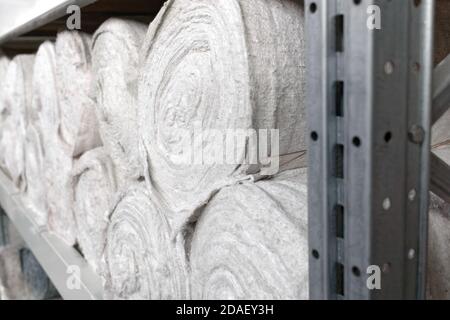 Weißes Material in Rollen befindet sich in den Regalen des Lagerhauses. Abdeckmaterial. Textilien für die Herstellung von Lumpen. Stockfoto