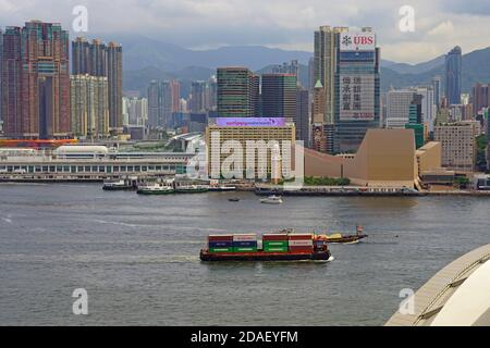 HONGKONG -30 JUN 2019- Blick auf ein Containerschiff im Hafen von Victoria vor der modernen Skyline Hongkongs. Stockfoto