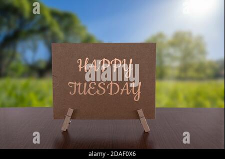 Happy Tuesday Karte auf dem Tisch mit sonnigen grünen Wald Hintergrund. Stockfoto
