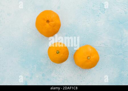 Mandarinenfrüchte isoliert auf blauem Hintergrund. Flach liegend. Leckere Zitrusfrüchte Stockfoto