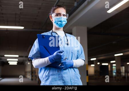 Medizinische Rettungskräfte tragen PSA-Uniform, Schutzbrille und Gesichtsmaske, halten Zwischenablage am mobilen Testzentrum, PCR Coronavirus COVID-19 Virus Diseas Stockfoto