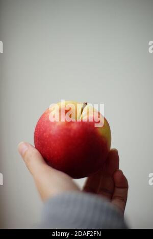 Reifer roter Apfel in weiblichen Fingern. Weißer Background. Seitenansicht. Stockfoto