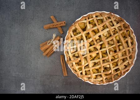 Frische Äpfel, Zimtstangen und klassische amerikanische Pie Draufsicht Foto. Grauer Hintergrund mit Kopierbereich. Stockfoto