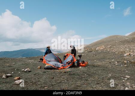 Russland, Dagestan - 21. September, 2020:zwei Männer haben auf dem Gipfel des Berges ein Touristenzelt aufgebaut. Stockfoto