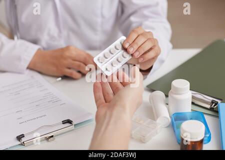 Nahaufnahme des Arztes, der am Tisch sitzt und Pillen gibt Ihre Patientin im Krankenhaus Stockfoto
