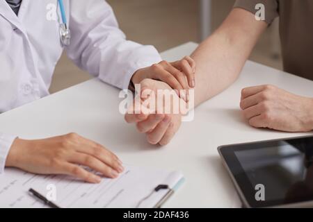 Nahaufnahme der Krankenschwester im weißen Mantel, die den Patienten während der Untersuchung untersucht Seinen Besuch misst sie seinen Puls Stockfoto